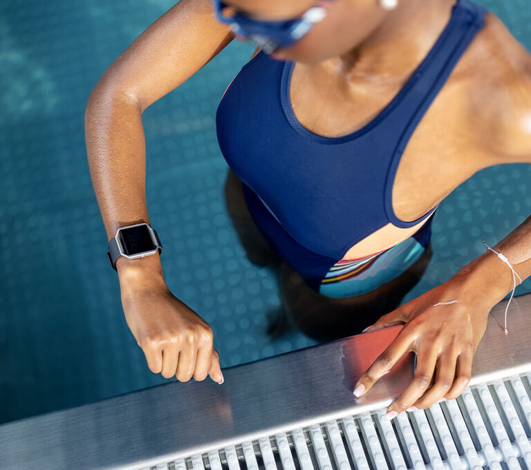 Ragazza che controlla lo smartwatch durante l'allenamento in piscina