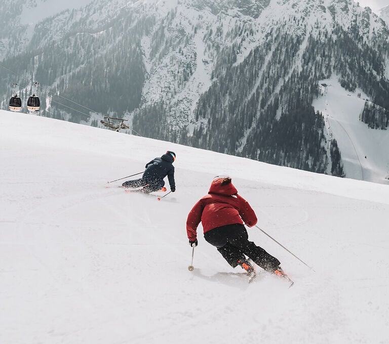 Due ragazzi che sciano sulla neve in montagna