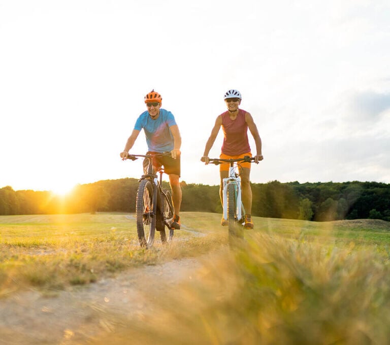 Ragazza e ragazzo che vanno in bici in montagna in estate