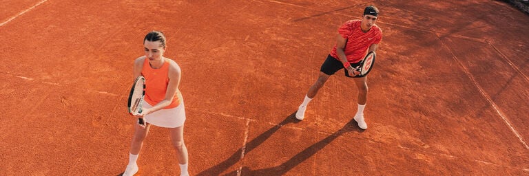 Gruppo di ragazzi che giocano a tennis su campo di sabbia rossa