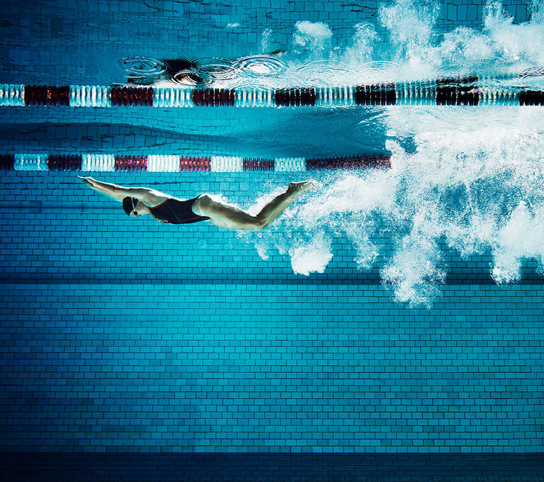 Ragazza che nuota immersa in piscina in stile delfino