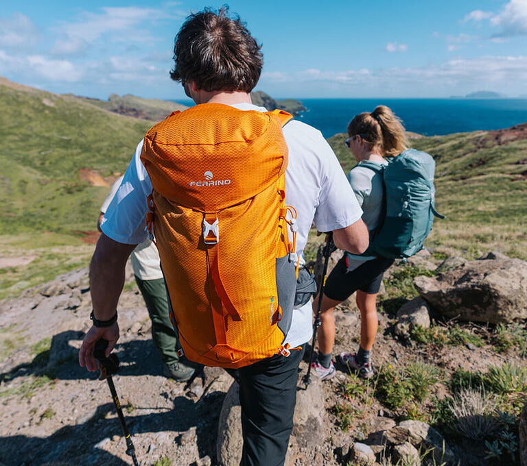 Ragazzo che fa trekking e porta zaino da escursionismo arancio Ferrino