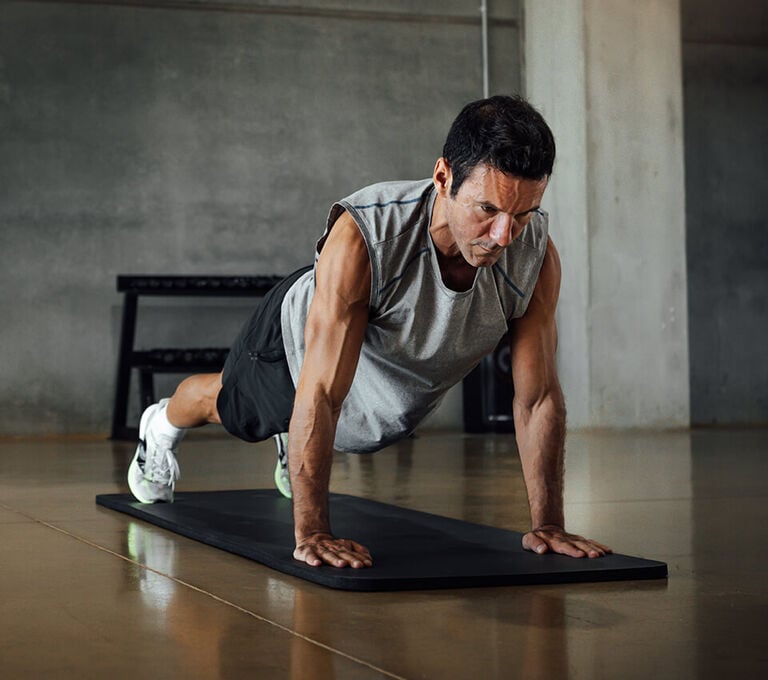 Ragazzo che fa plank su tappetino in palestra