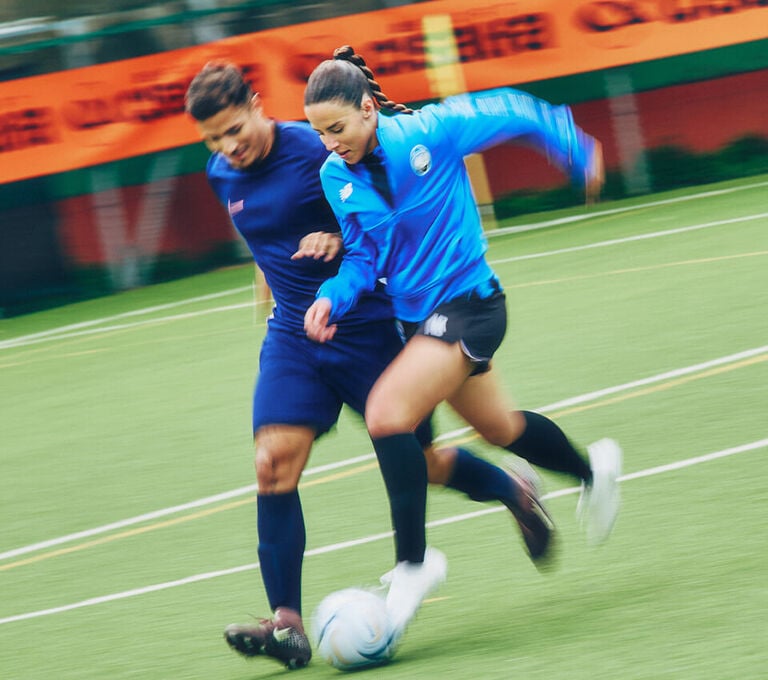 Ragazza e ragazzo che si scartano a calcio durante un'allenamento