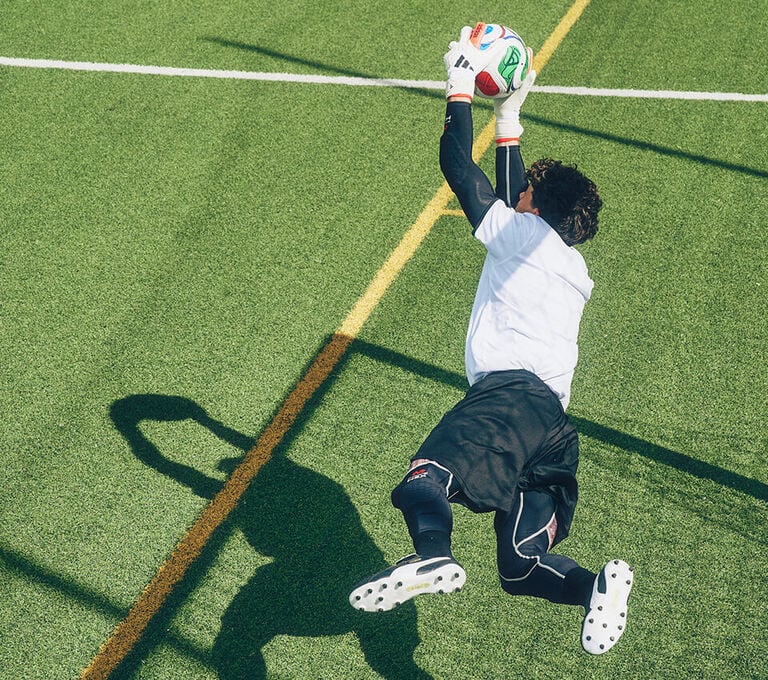 Ragazzo che si lancia per parare un pallone diretto in porta