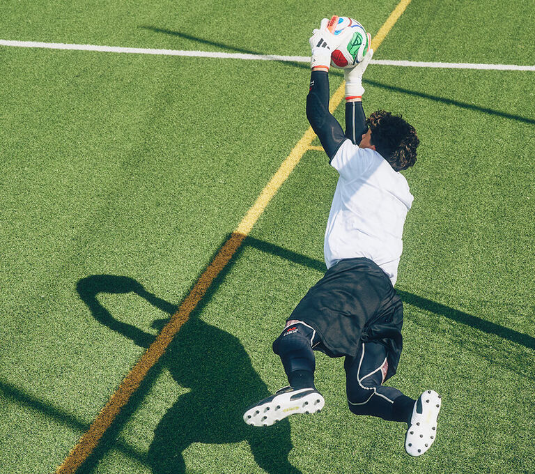 Ragazzo che si lancia per parare un pallone diretto in porta