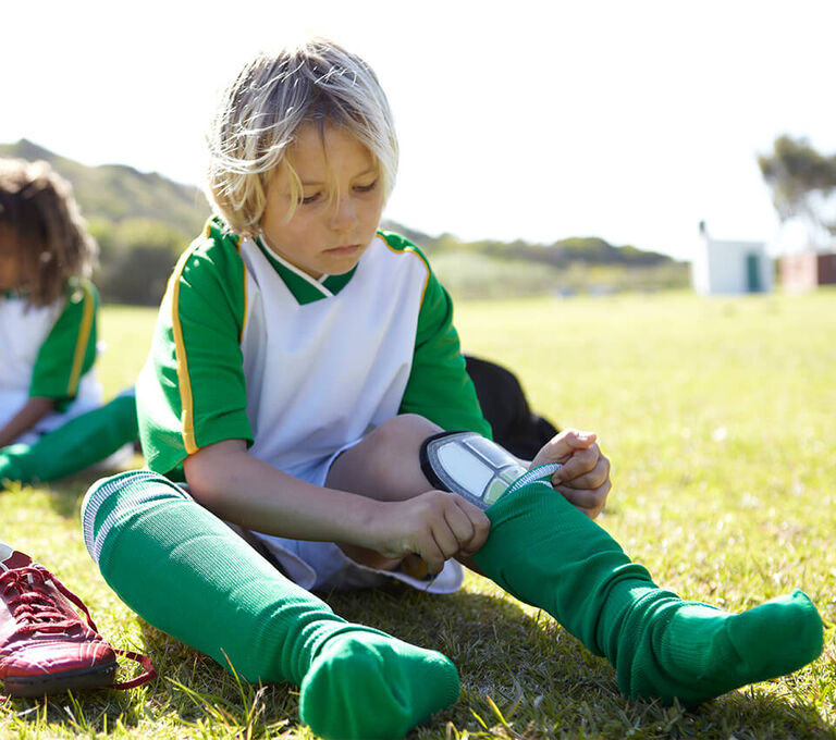 Bambino che indossa i parastinchi prima di una partita di calcio