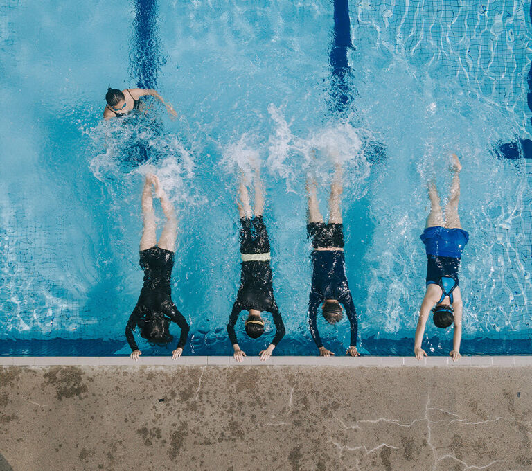 Gruppo di persone che riscladano le gambe in acqua prima di iniziare l'allenamento