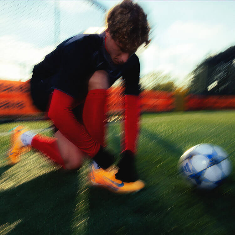 Ragazzo sul campo da calcio che si sta allacciando le scarpette prima di iniziare la partita