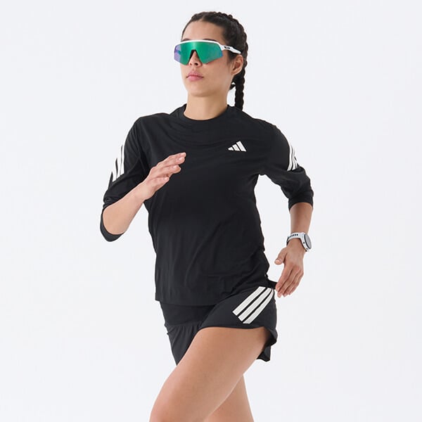 Ragazza vestita con completo adidas e scarpe asics che corre