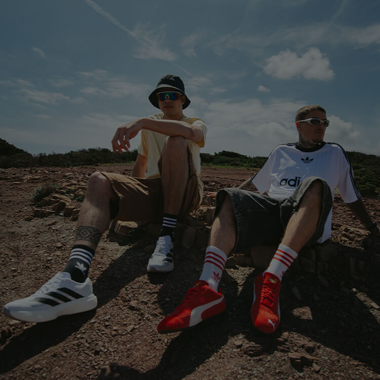 Due ragazzi seduti in spiaggia e vestiti lifestyle alla moda