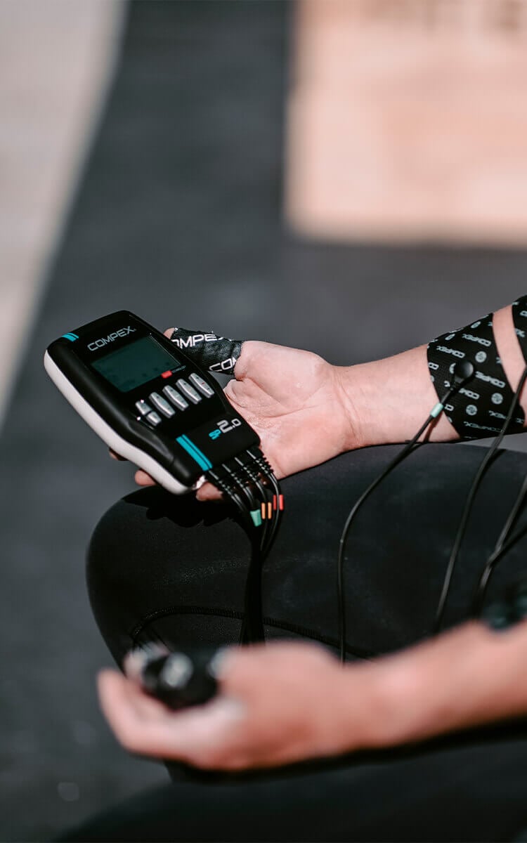 Ragazza che utilizza elettrostimolatore Compex sul braccio