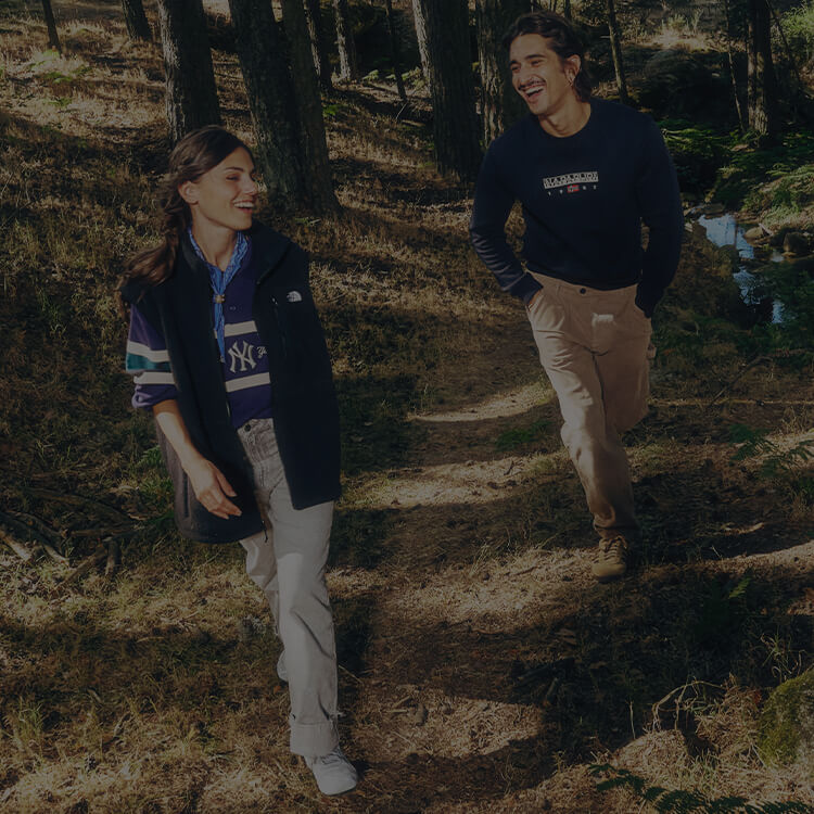 Ragazza e ragazzo che camminano su un sentiero e sono vestiti con abbigliamento urban dei top brand