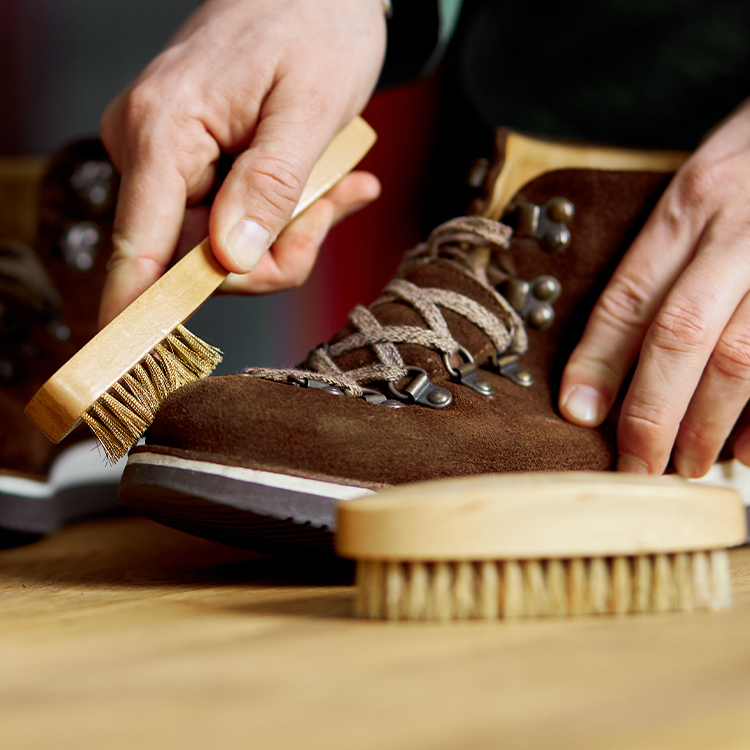 Ragazzo che pulisce scarponi da montagna in pelle scamosciata