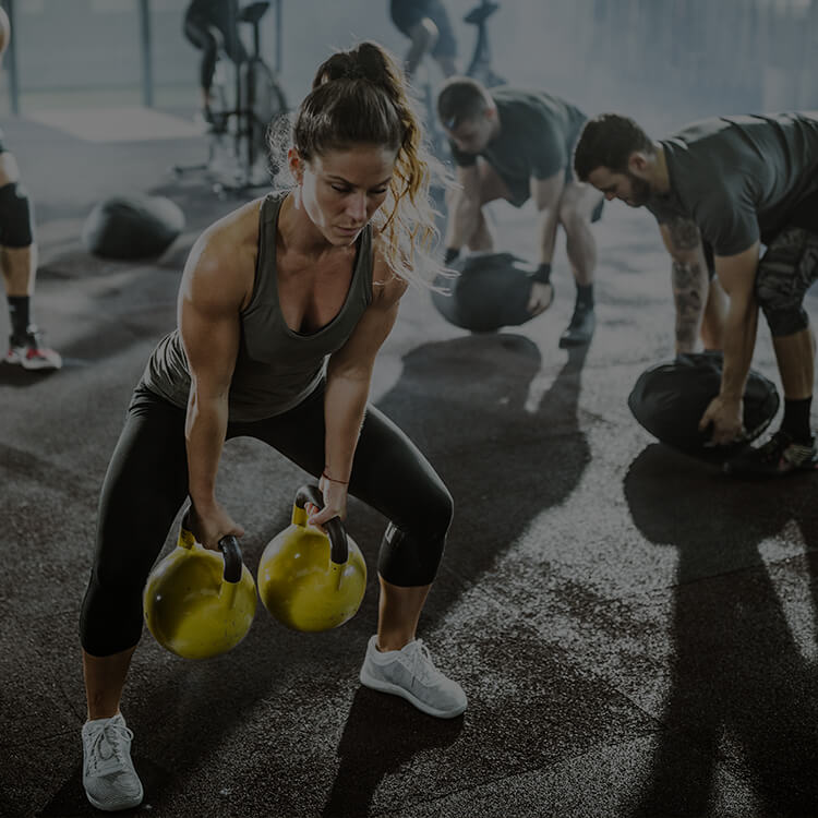 Gruppo di persone che si allena in palestr, alzando pesi e palle mediche