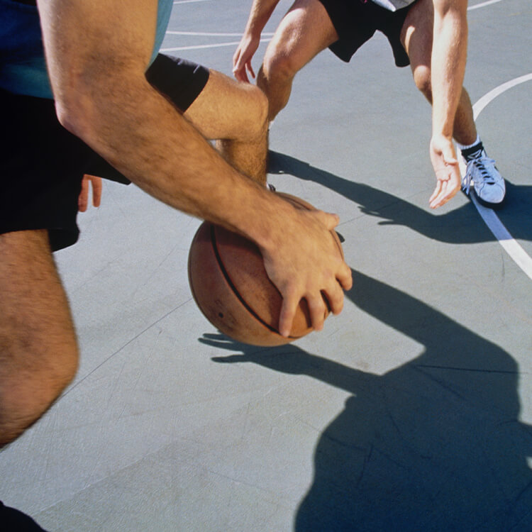 Ragazzo che gioca a basket in campetto all'aperto