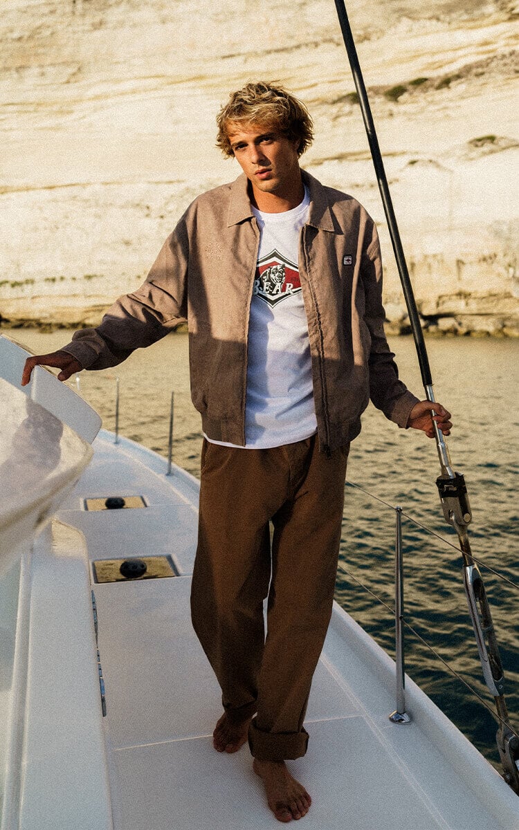 Ragazzo su una barca che indossa abbigliamento Bear Surfboards