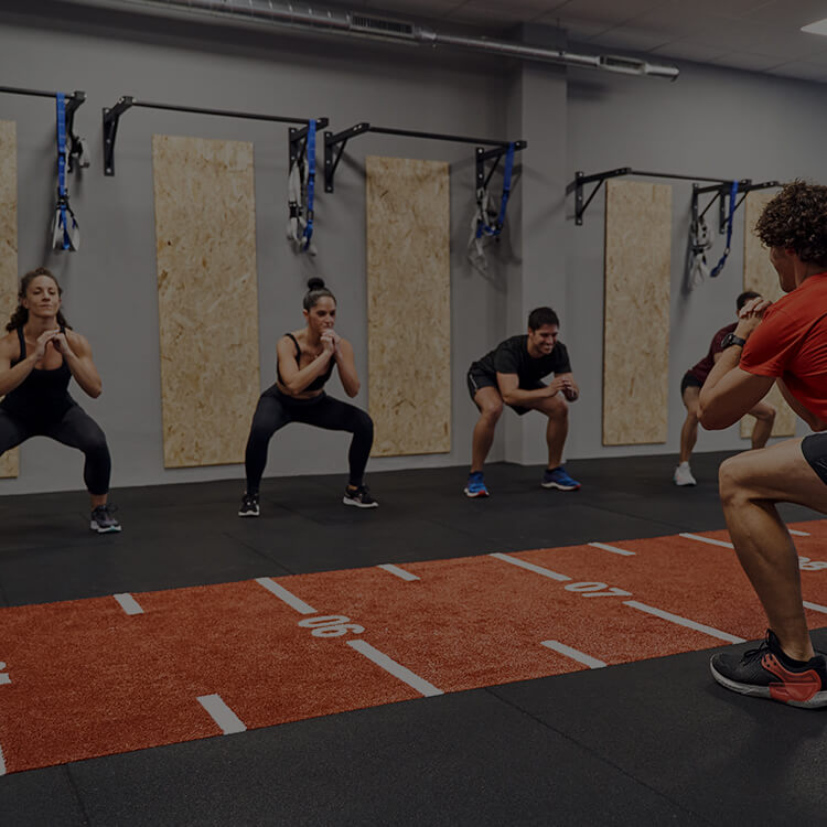 Gruppo di persone che si allena in palestra facendo squat