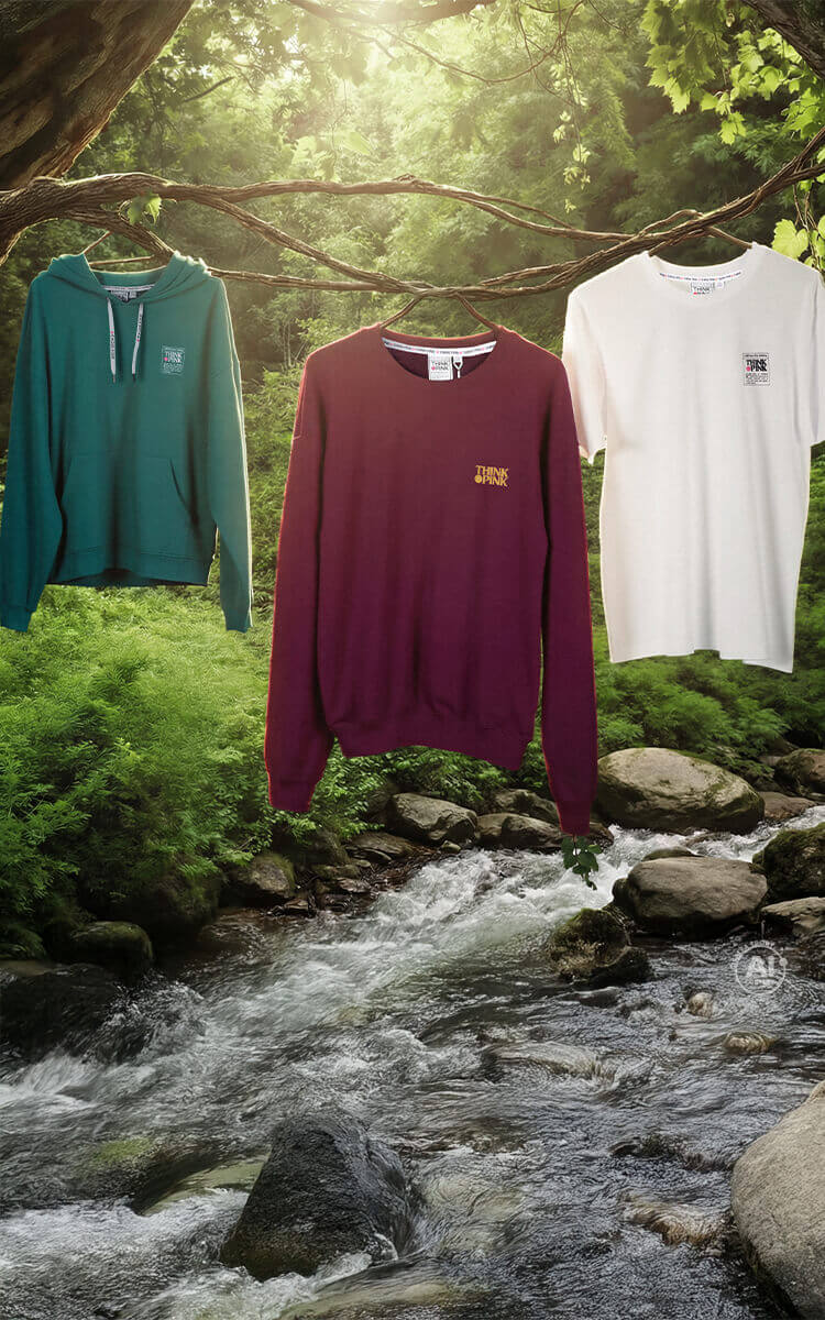 Tre capi d'abbigliamento Think Pink appesi su dei rami in una foresta