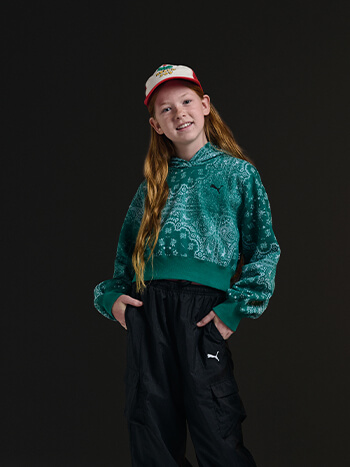 Bambina con cappellino, felpa verde e pantaloni tuta Puma neri