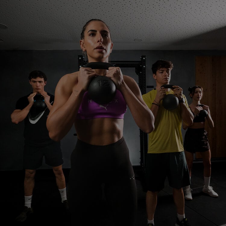Gruppo di persone che si alleano in palestra con Kettle Bells