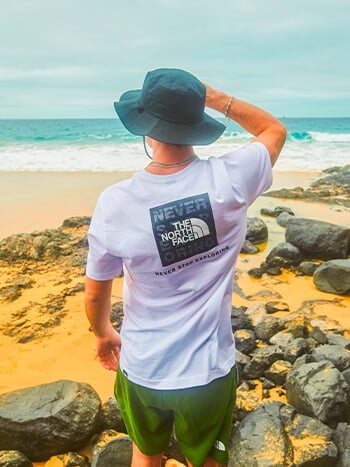 Ragazzo che guarda il mare e indossa tshirt The North Face